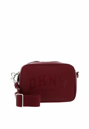 Sac bandoulière rectangulaire en cuir bordeaux avec bandoulière en tissu ajustable et logo DKNY New York embossé sur le devant.