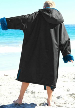 Schwarze Oberbekleidung mit Kapuze und leuchtend blauen Fleecebündchen. Das Material ist glatt, und das Design ist übergroß mit seitlichen Schlitzen.