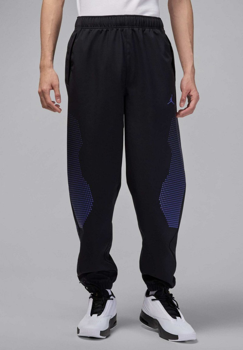 Zwarte joggingbroek met een elastische tailleband, voorzien van een getextureerd blauw geometrisch patroon aan de zijkanten en aansluitende boorden bij de enkels.