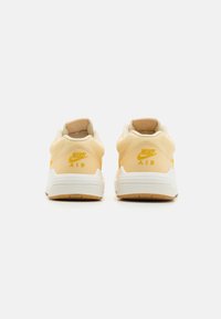 Yellow Nike Air sneakers with a smooth leather upper, white midsole, and rubber outsole; features embroidered logo at the heel.
