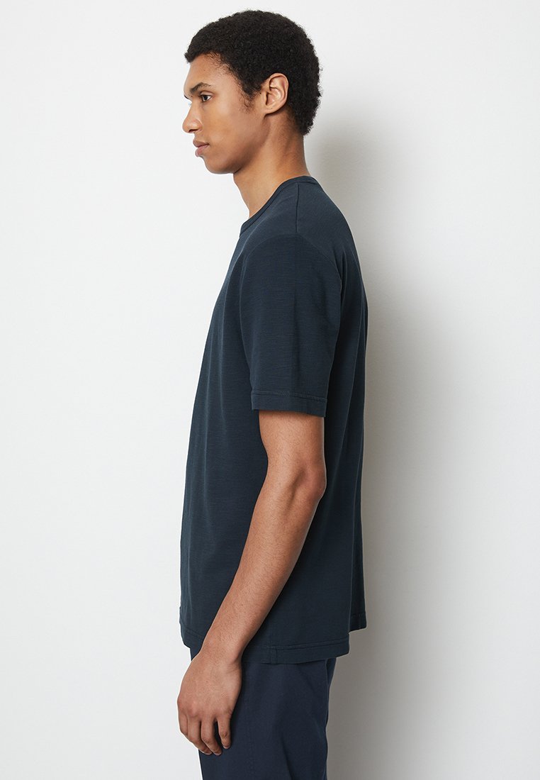 Granatowa koszulka polo z krótkim rękawem, okrągły dekolt, wykonana z miękkiego materiału, luźny krój, z gładką teksturą i subtelnymi detalami w stich.