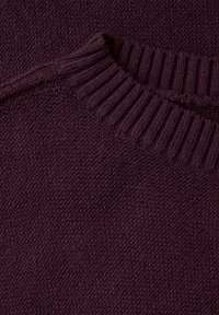 Tessuto di maglione lavorato a maglia di un viola vibrante con scollo a coste; texture liscia e trama ariosa, che mostra un design semplice e classico.
