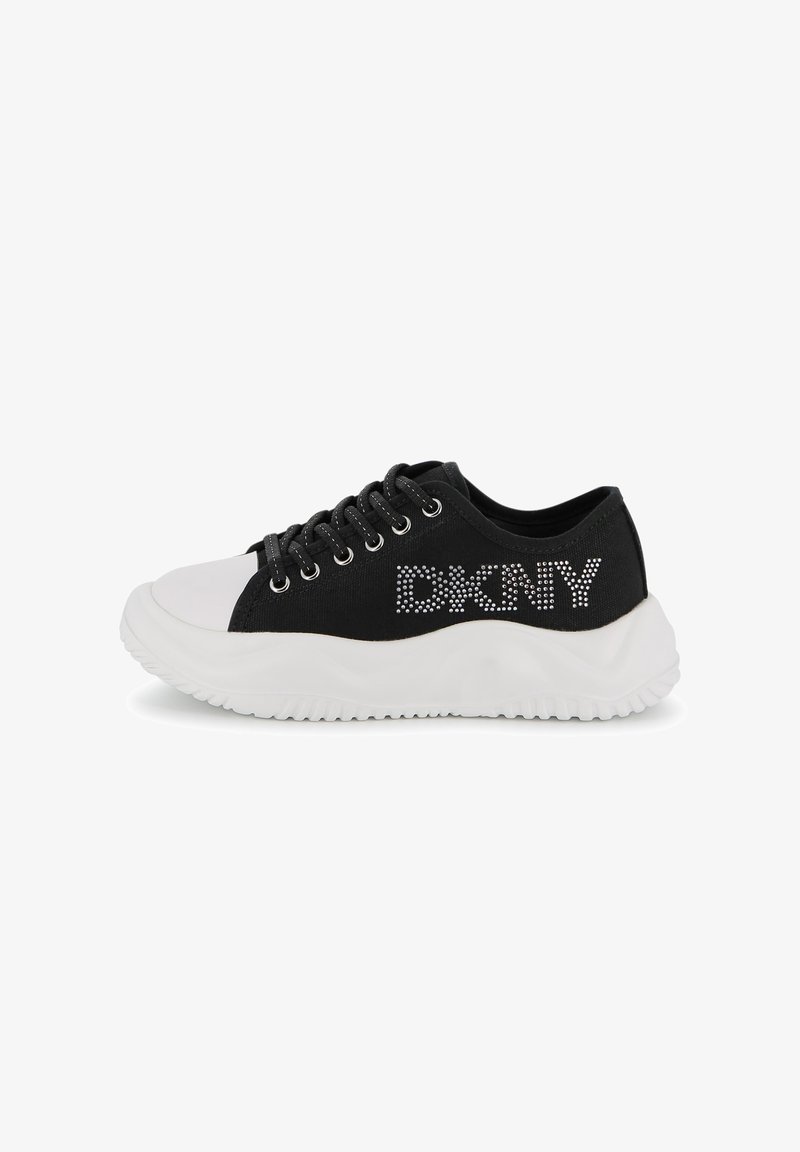 Baskets basses noires avec semelle épaisse blanche, bout blanc, lacets noirs, et logo "DKNY" en strass blancs sur le côté.