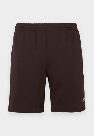 Shorts di cotone con vita elastica marrone scuro, con un piccolo logo ricamato verde e bianco vicino all'orlo inferiore sulla gamba destra.