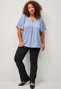 Light blue, short-sleeve top with a V-neck and pleat detail, paired with black pants and flat black shoes. Smooth fabric texture.