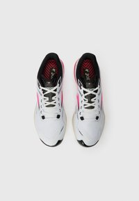 Een paar witte hardloopschoenen met roze accenten en een zwarte binnenvoering, van bovenaf bekeken op een witte achtergrond.