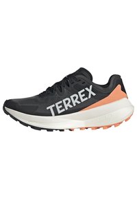 Crne atletske tenisice s pletenom gornjom, bijelim logotipom "TERREX", teksturiranim crnim vrhom, breskvastim naglaskom na peti i pjenastim bijelim srednjim slojem.