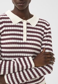 Randig stickad tröja med vit krage, med vinröda och vita horisontella ränder, texturerat tyg och knappstängning fram.