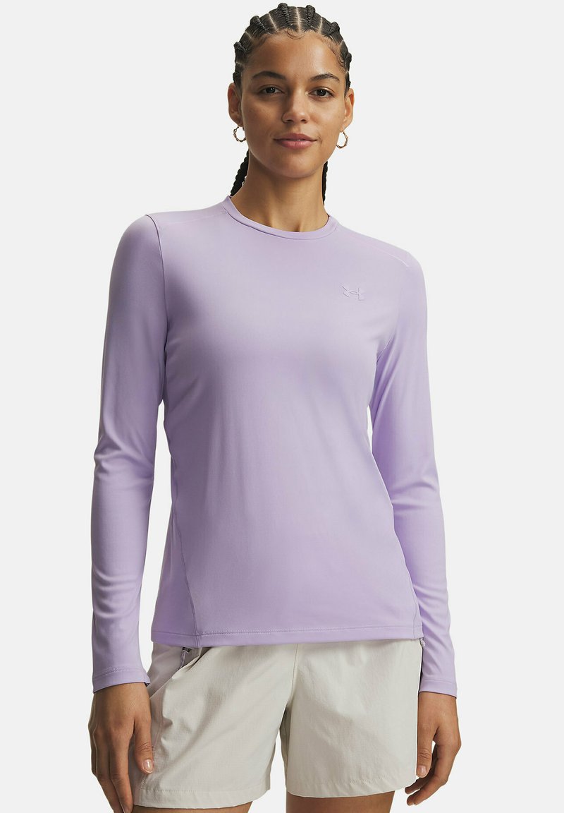 Hellviolettes Langarmshirt mit Rundhalsausschnitt und einem dezenten Logo auf der Brust. Glatter, elastischer Stoff. Kombiniert mit hellen Shorts.