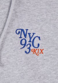 Grå sweatshirtstof med farverig broderi med "NYC 93 C K1X" i blå og orange bogstaver. Blød tekstur, ingen mønstre eller yderligere detaljer.