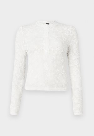 Camicia bianca a maniche lunghe con un motivo floreale texturizzato, girocollo e una pattina con due bottoni sul davanti.