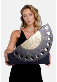 Kreisförmige Mondphasenanzeige mit einem Gold- und Schwarzfarbschema, gravierten Mustern und Halbmondausschnitten auf einem dunklen Untergrund.