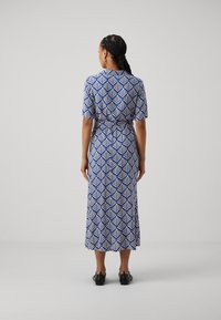 Maxi dress in blue and white leaf pattern, short sleeves, cinched waist, soft fabric, and a relaxed silhouette. Shoes are black.