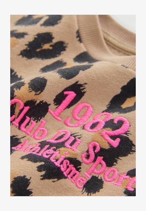 Leopardenmusterstoff in Beige- und Schwarztönen, mit pinker gestickter Aufschrift: "1962 Club Du Sport Athlétisme." Weiche Textur.
