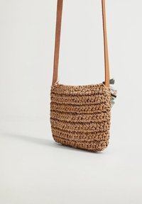 Borsa a tracolla intrecciata in paglia marrone chiaro con una tracolla in pelle liscia. Caratterizzata da un corpo testurizzato e dettagli in tessuto pastello su un lato.
