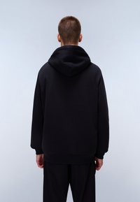 Black hooded sweatshirt with a relaxed fit, crafted from soft material, featuring a ribbed hem and cuffs, shown from the back.