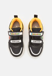 Zwarte synthetische sneakers met een gele binnenkant, voorzien van klittenbandsluitingen met "Super Mario" en "GEOX". Gelaagde bovenkant en witte zool.