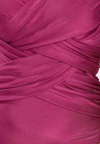 Gros plan sur un tissu magenta avec des plis superposés et une texture lisse, mettant en valeur le drapé et les plis détaillés.