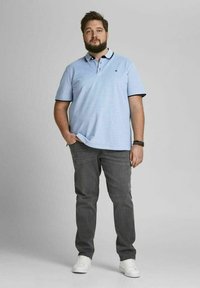 Lichtblauwe polo met een contrasterende kraag, gecombineerd met donkergrijze jeans en witte sneakers. Heeft korte mouwen en een relaxte pasvorm.