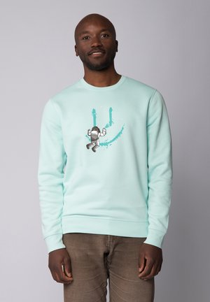Mintgrüner Sweatshirt mit Rundhalsausschnitt und langen Ärmeln, versehen mit einem Grafikdesign eines Astronauten und Farbspritzern in Türkis.