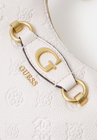 Witte leren handtas met reliëf-logo patronen, gouden hardware accenten, een "G"-logo en een contrasterende stiknaad.