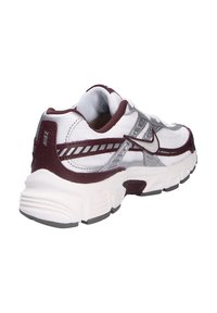Las zapatillas Nike cuentan con una parte superior de malla blanca con acentos en color burdeos, una entresuela gris texturizada y un talón reforzado para mayor soporte.