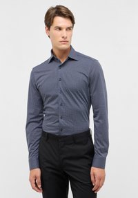 Blauwe lange mouwen overhemd met een klein wit geometrisch patroon, button-down kraag en een slim fit, gecombineerd met zwarte broek.