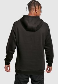 Felpa con cappuccio nera, dal texture morbido, con polsini e vita a coste. Presenta un cappuccio ampio in un design classico.