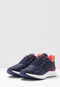 Námořnické sportovní boty s texturovaným svrškem, růžovými akcenty na patě a tkaničkách a bílou podrážkou se vzorem pro lepší přilnavost.