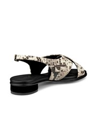 Slingback-Sandale aus strukturiertem, schlangen-musterigem Material; die Farben umfassen Creme und Schwarz; verfügt über einen niedrigen Blockabsatz und ein offenes Zehendesign.