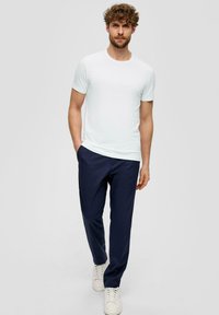 Camiseta blanca de manga corta combinada con pantalones azul marino y zapatillas blancas, con un ajuste simple y relajado y una textura suave.