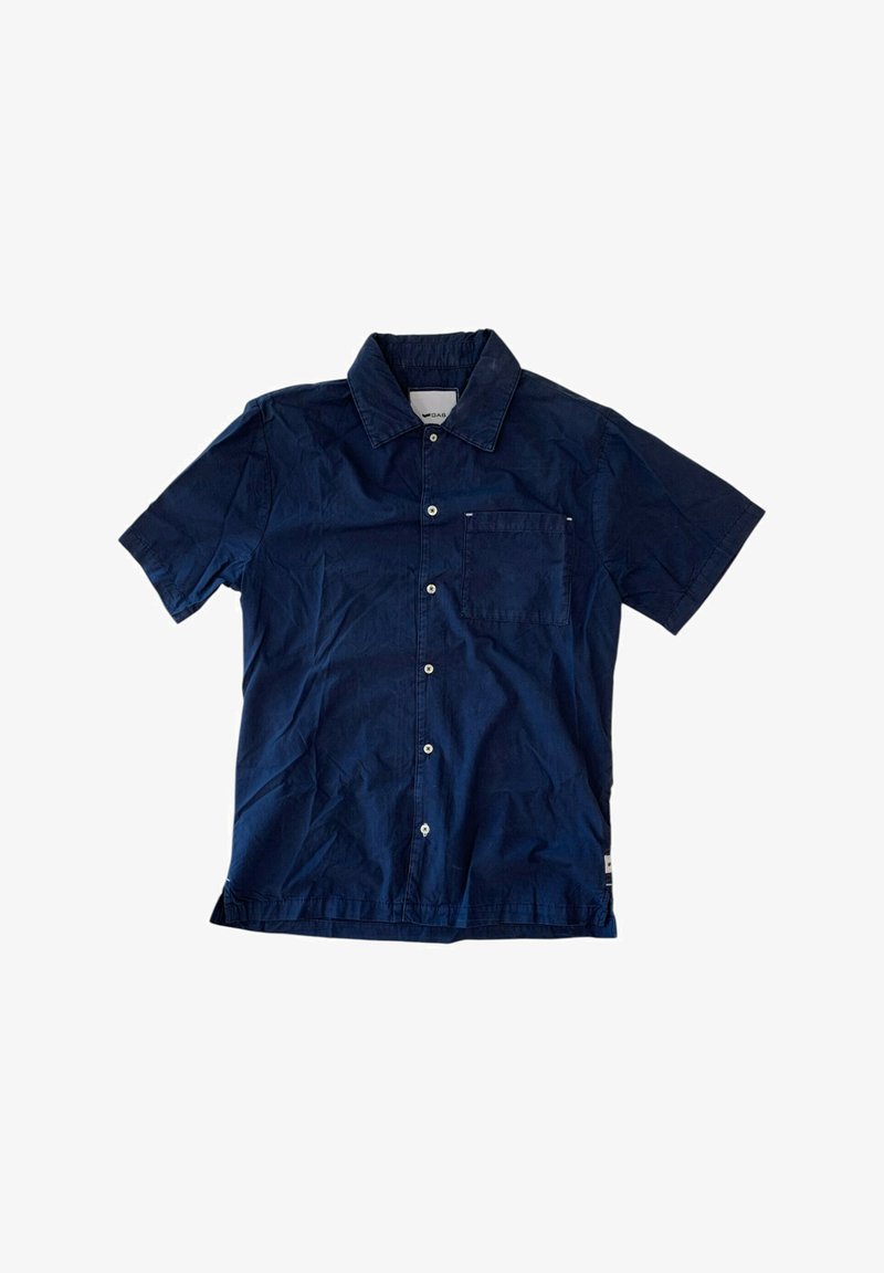 Camicetta con colletto a maniche corte in blu navy. Realizzata in tessuto leggero, presenta una tasca frontale e chiusura con bottoni bianchi.