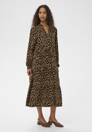 Vestido largo con estampado de leopardo en tonos marrón claro y negro, con escote en v, mangas largas y falda con volantes. Combinado con zapatos marrones de tacón con correa en el talón.