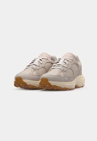 Ljust beige sneakers med en blandning av mocka och meshmaterial, med texturerade accenter, en tjock dämpad sula och vita snören.
