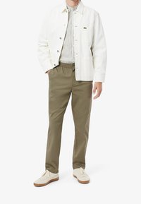 Biała bawełniana kurtka na zatrzaski, pasiasta koszula, oliwkowe spodnie chino oraz kremowe tenisówki z teksturowanej tkaniny z gumową podeszwą.