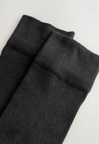 Sorte strikstrømper med en tekstureret ribbet kant og glat krop. Materialet er blødt, med en ensartet farve og et minimalistisk design.