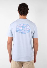 Camiseta de manga corta azul claro con un gráfico circular que presenta el texto "MANTENTE VIVO" y acentos florales en la parte posterior. Material de algodón suave.