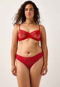 Rød blondebh og matchende trusser med blomsterbroderi, gennemsigtige paneler og en lille sløjfedetalje. Justerbare stropper og elastisk talje.