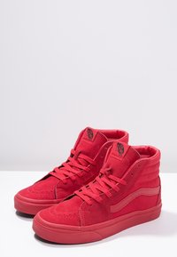 Zapatillas altas rojas de ante con cordones a juego, lados ventilados y detalles texturizados en la punta. Suelas de goma para mayor durabilidad y tracción.