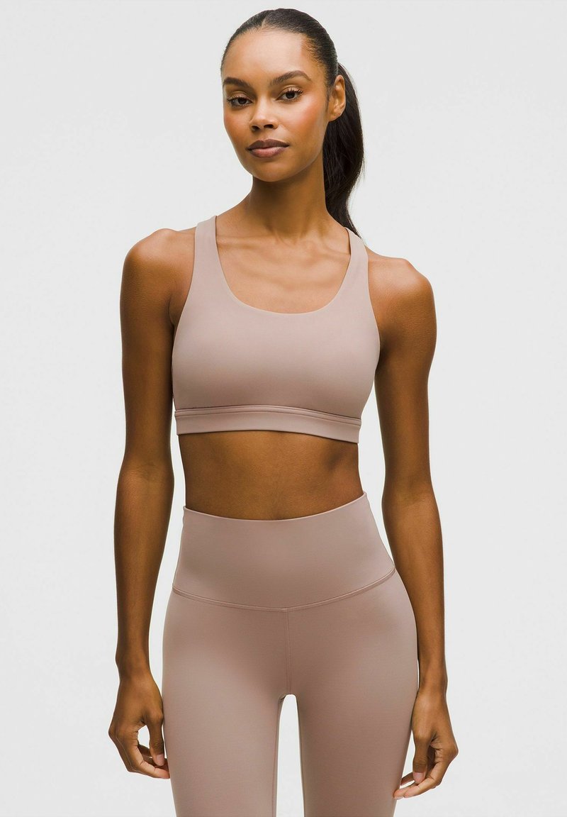 Hellbrauner Sport-BH mit einer glatten, dehnbaren Textur; verfügt über breite Träger und ein schlichtes Design. Getragen mit passenden hoch taillierten Leggings.