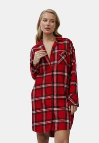 Camicia da donna in flanella a quadri rossi e neri, con maniche lunghe, chiusura a bottoni, taschino sul petto e una vestibilità rilassata e oversize.