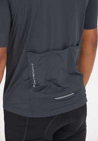 Dunkelgraues kurzärmliges Sportshirt aus strukturiertem Stoff, mit Rückentaschen, reflektierenden Akzenten und einem Logo mit dem Wort "ENDURANCE".