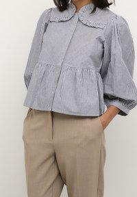Gestreepte katoenen blouse met een ronde kraag, pofmouwen en plooien in de taille, gecombineerd met op maat gemaakte beige broek.