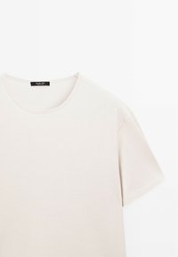 Light beige short-sleeve t-shirt made of soft cotton, featuring a round neckline and minimal seams, designed for a relaxed fit.