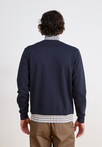 Navy blue sweatshirt with long sleeves, round neckline, and checkered patterned hem. Smooth texture, casual design, view of the back.