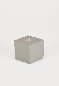Szara teksturowana pudełko z trójkątnym złotym logo na górze, z kwadratowym wzorem i złożonymi narożnikami, co nadaje elegancki wygląd.