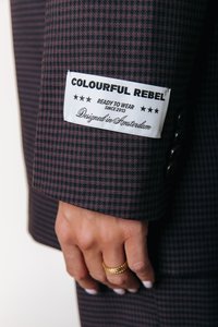 Czarna marynarka w kratę z metką "Colourful Rebel" na mankiecie. Materiał jest teksturowany z głębokim bordowym i czarnym wzorem.