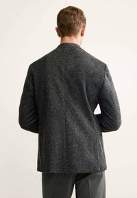 Blazer grigio a spina di pesce con tessuto strutturato, rever a punta e maniche lunghe. Vestibilità leggermente sagomata con uno spacco sul retro per il movimento.