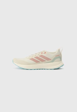 Beige athletic shoe with pink accents and three side stripes. Features a rounded toe, textured sole, and lightweight, water-repellent material.