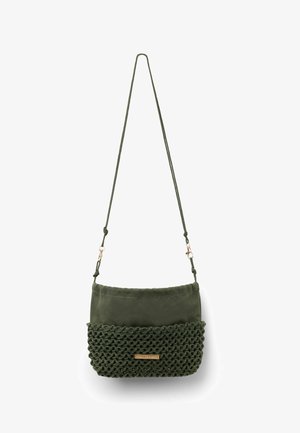 Sac bandoulière vert foncé avec moitié inférieure tissée, moitié supérieure lisse, sangle ajustable et petite plaque de marque rectangulaire dorée.